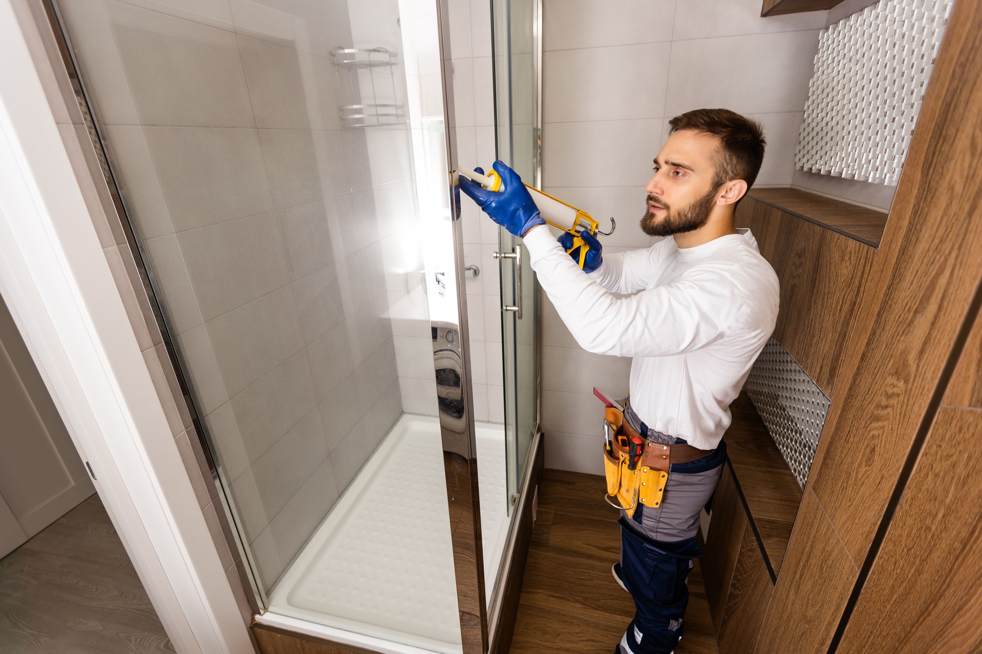 Young plumber fixing shower cabin