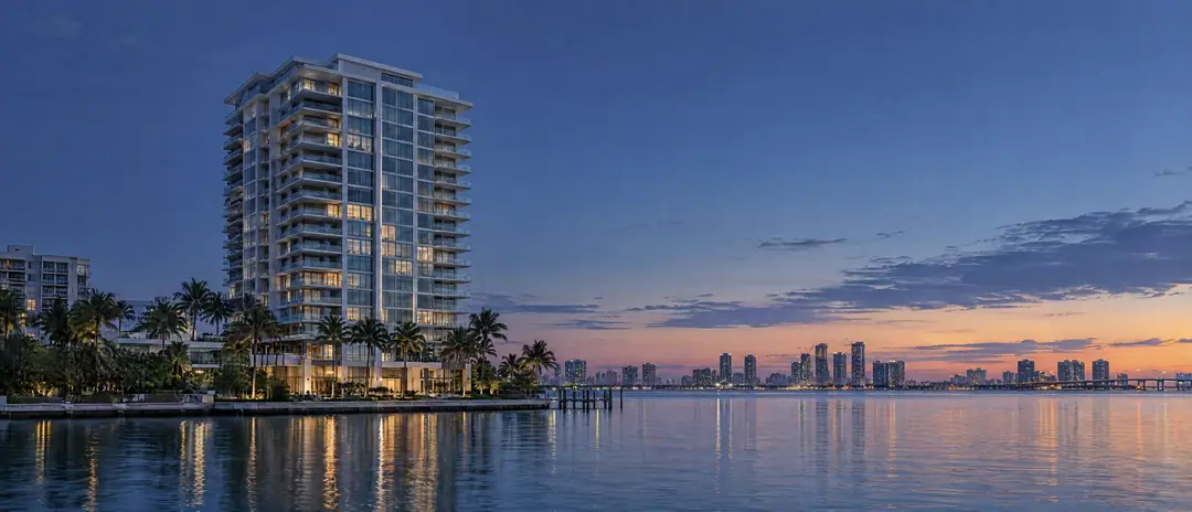 A residential tower beside Biscayne Bay at blue hour, a few windows lit